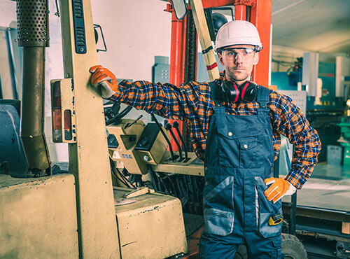 Lawaai in industriehallen en werkplaatsen Een productiemedewerker met gehoorbescherming in een luidruchtige industriehallen of werkplaats.