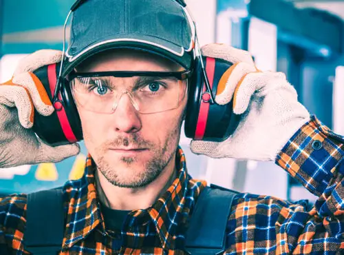 Een productiemedewerker maakt gebruik van gehoorbescherming om zich te beschermen tegen het lawaai.