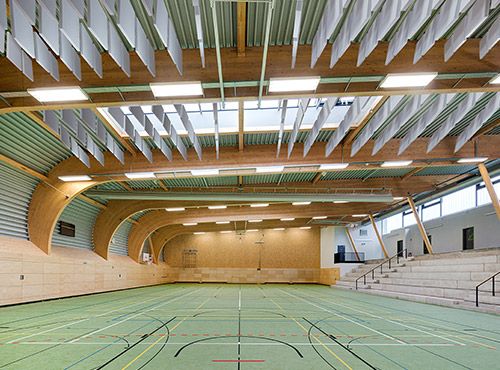 Absorptieplaten aan het plafond van een sporthale Vrij zwevende absorptieplaten aan het plafond van een sporthal verlagen het geluidsniveau en reduceren de nagalm.