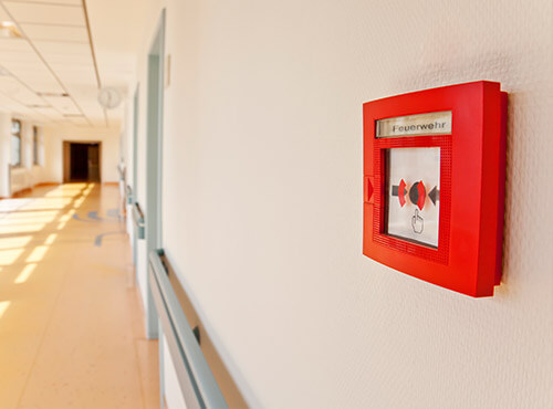 Geluidswering en brandveiligheid voor scholen en in de kinderopvang Brandmelder op de gang van een school met geluidwering en geluiddemping